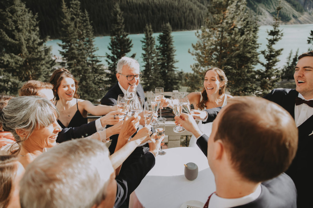 Wedding table toasts with champagne on terrace of Lake Louise wedding venue